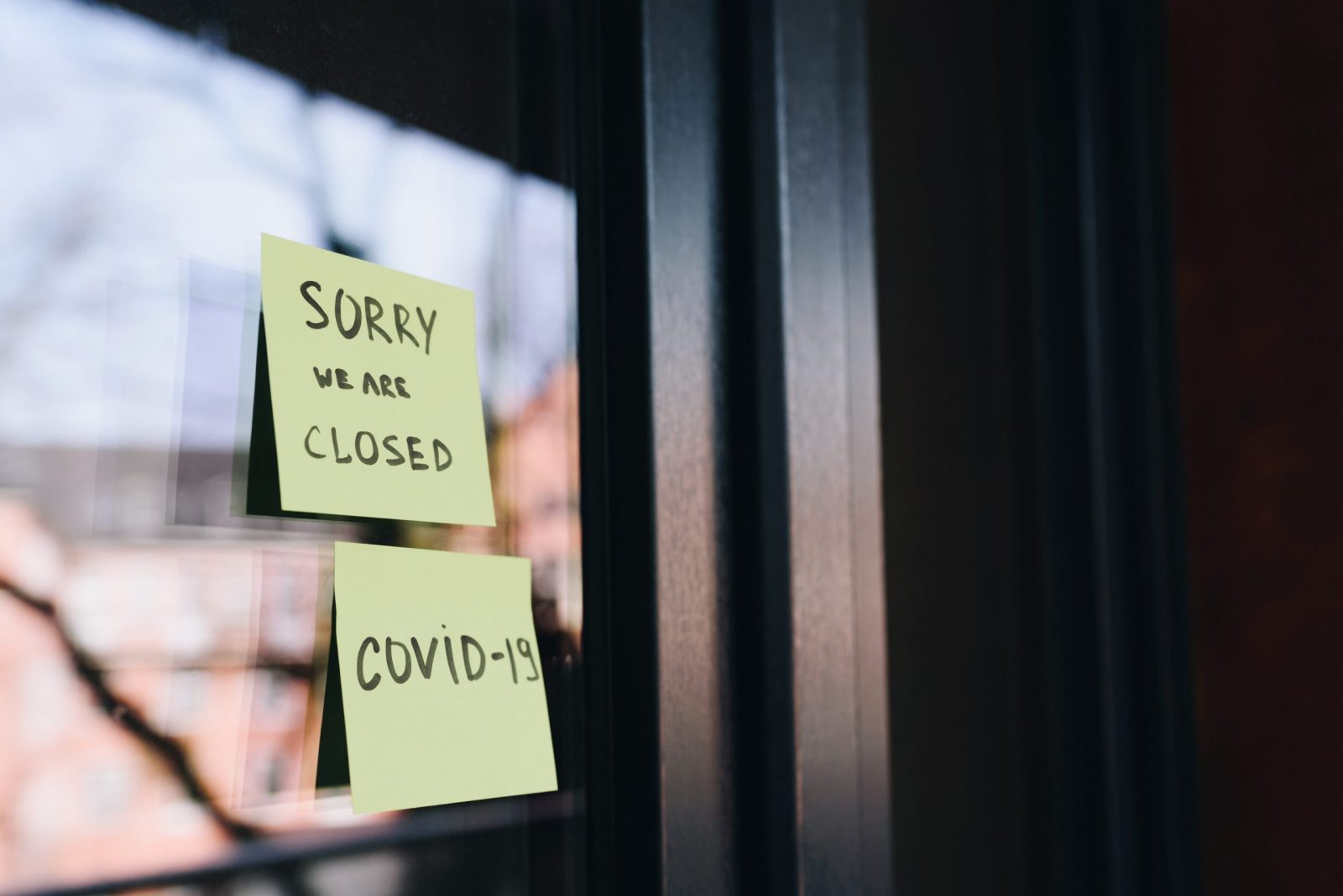 Shop with post its on the window of the front door saying'Sorry we are closed' and -Covid-19'